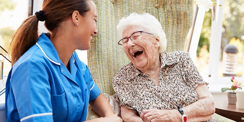 Elderly woman laughing with nurse